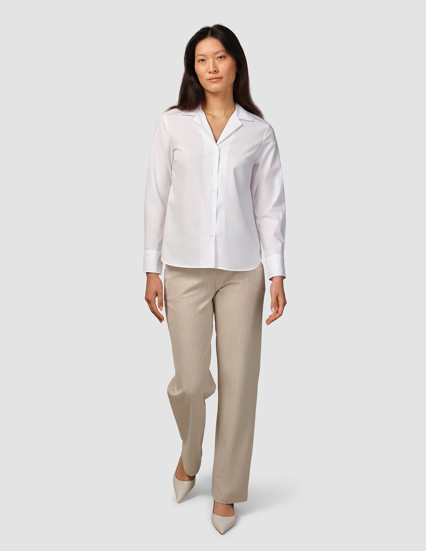 A woman wearing a Madison Shirt White and beige pinstriped trousers.
